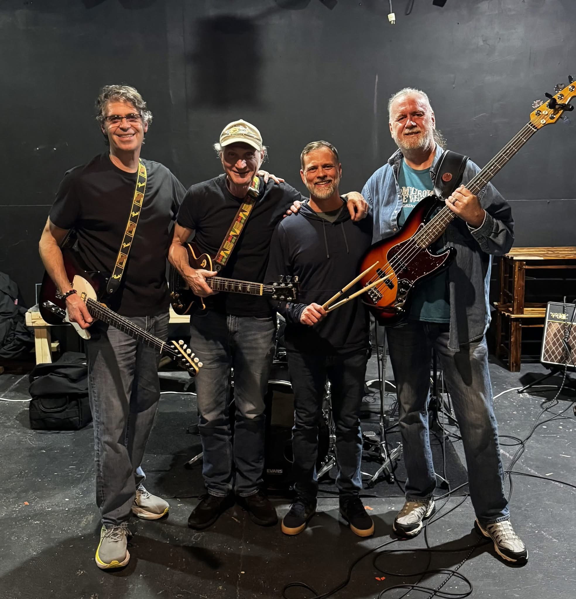 The four members of the Paul Stone Project smiling together on stage with their instruments